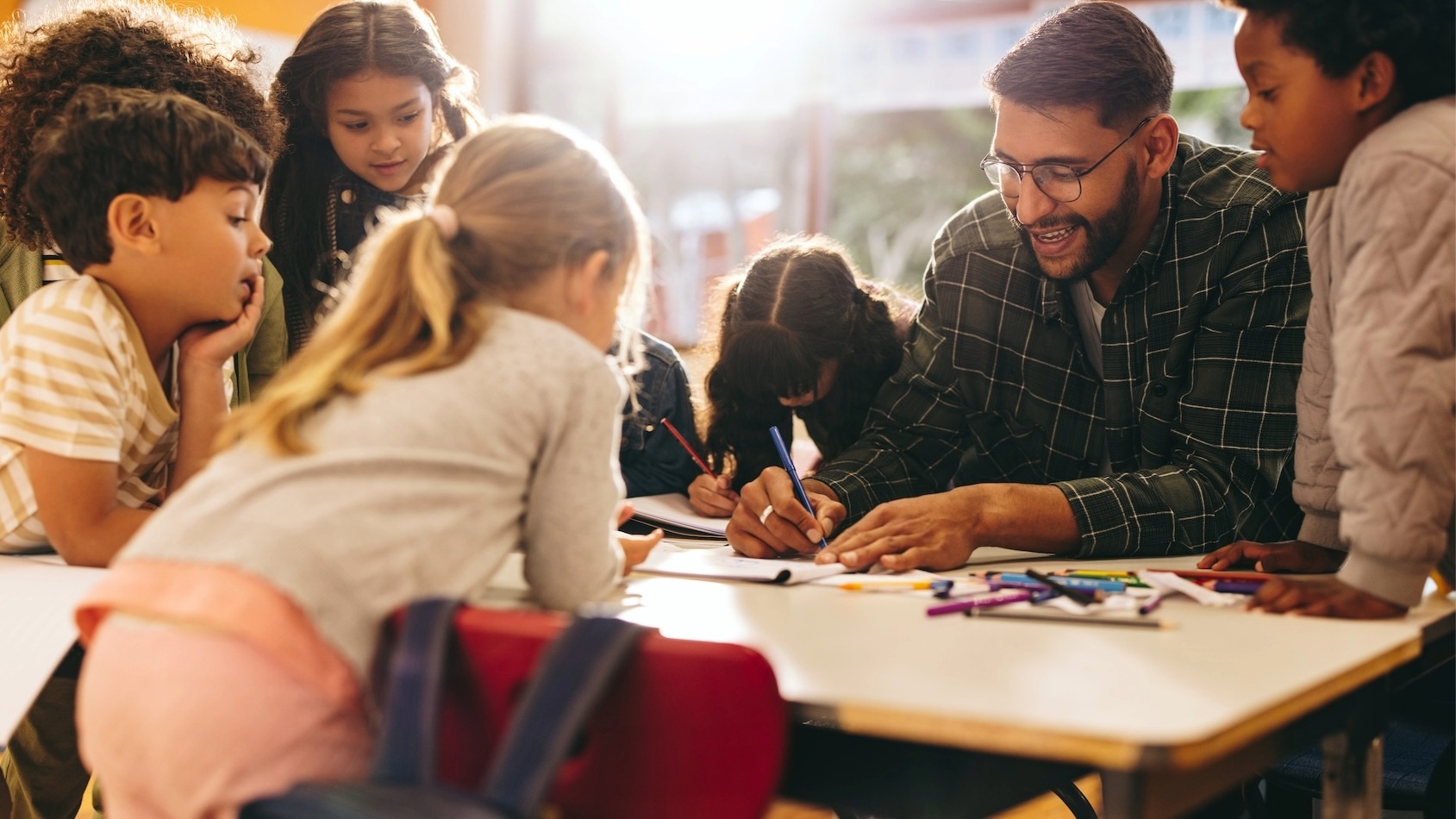 Grundschulkinder arbeiten gemeinsam mit einer Lehrkraft an einer Aufgabe und werden individuell begleitet. - HEBO Privatschule