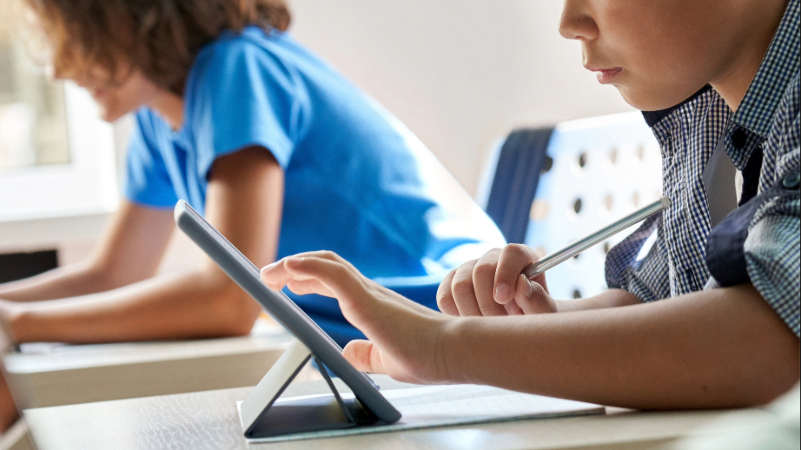 Schülerin und Schüler arbeiten konzentriert mit Tablet im Unterricht, eine ruhige Lernumgebung für Kinder mit ADHS in der Schule