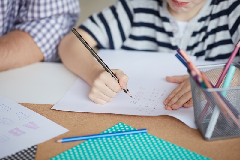 Kind bearbeitet Aufgaben mit Begleitung als Symbol für individuelle Unterstützung bei Tourette und Tics an der HEBO-Privatschule Mönchengladbach